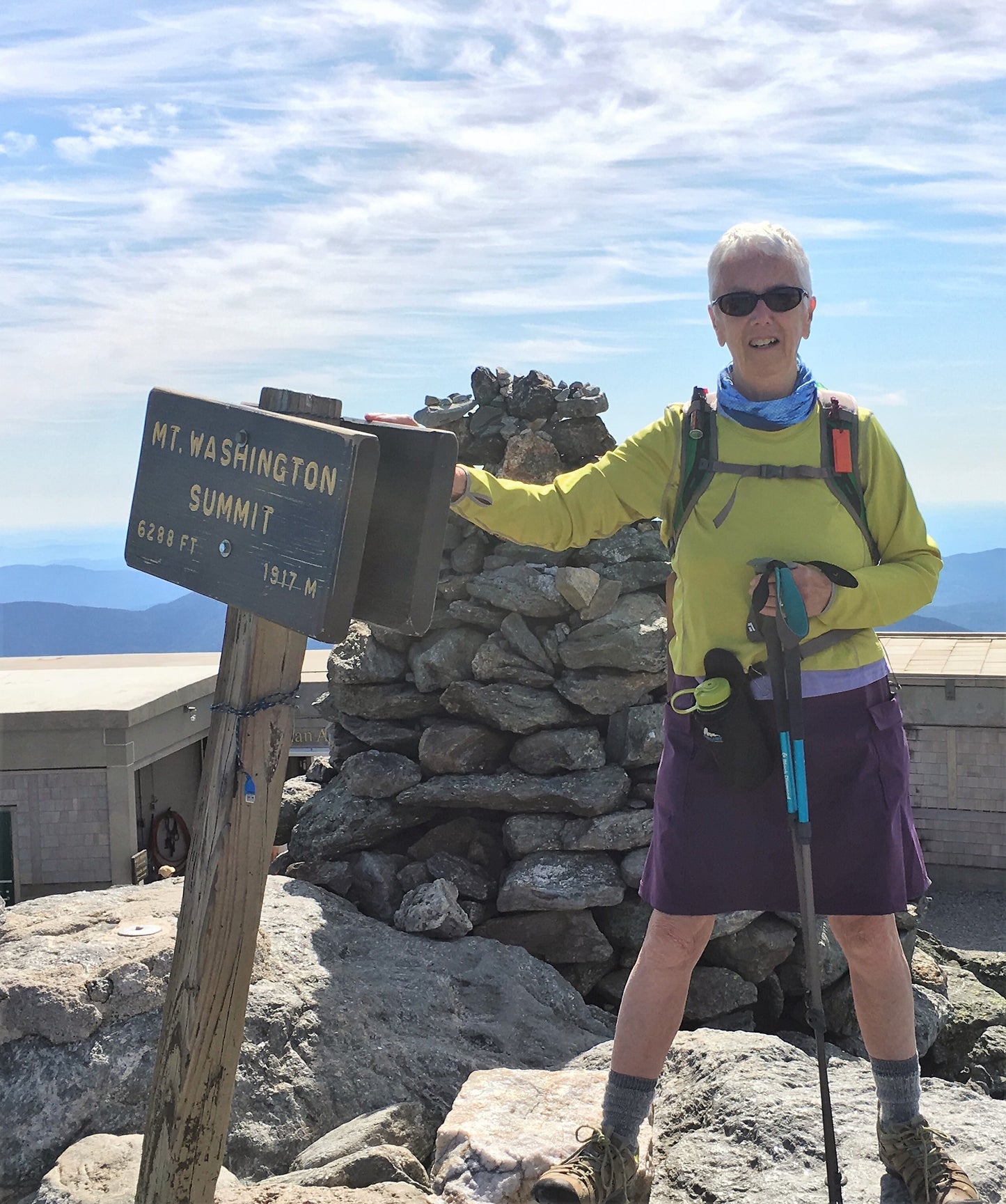 Person at the summit of Mount Washington with a sign in the background
