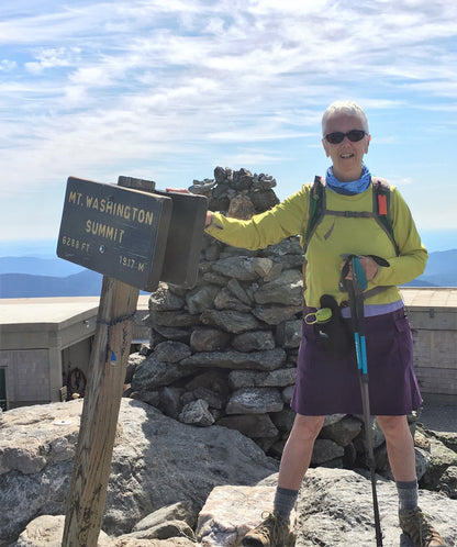 Person at the summit of Mount Washington with a sign in the background