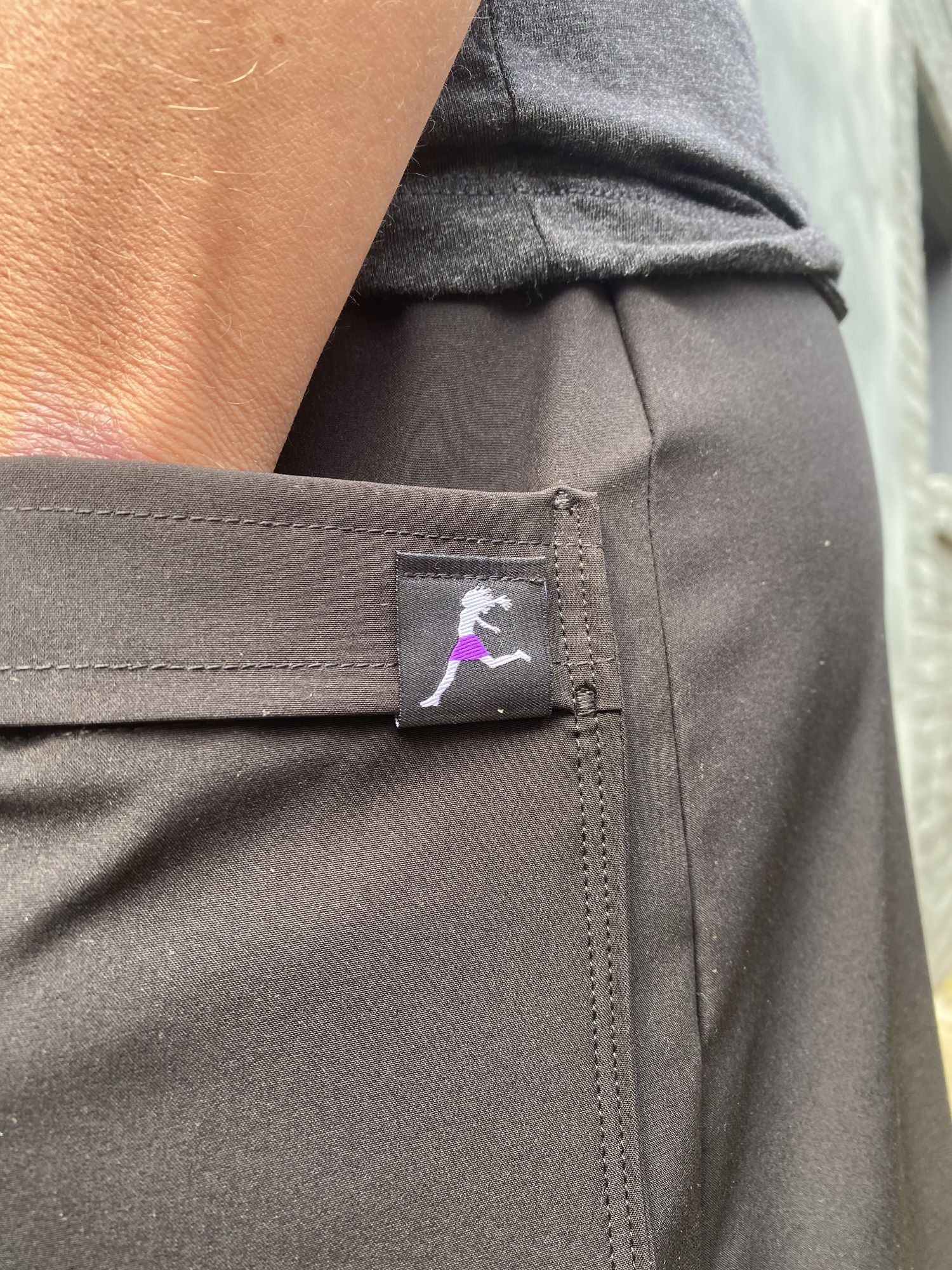 Close-up of a gray pants pocket with a brand logo on a blurred background