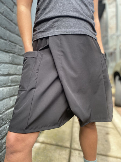 Person wearing gray shorts and a t-shirt against a brick wall.