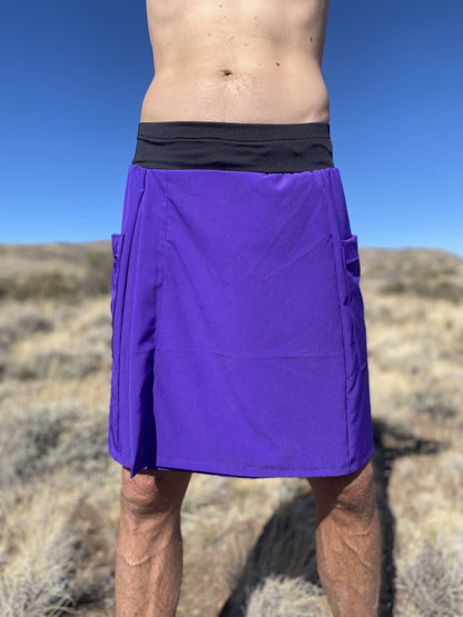 Person wearing a purple rain kilt with a black waistband in a desert setting.