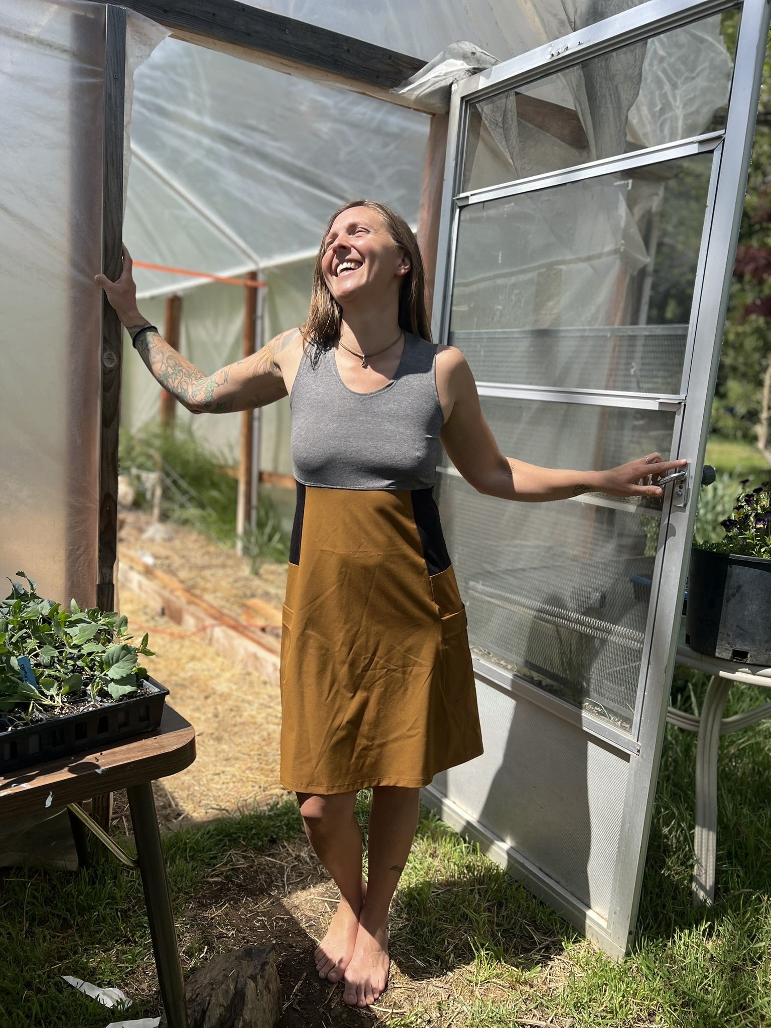 Woman standing in a greenhouse with plants and tools around