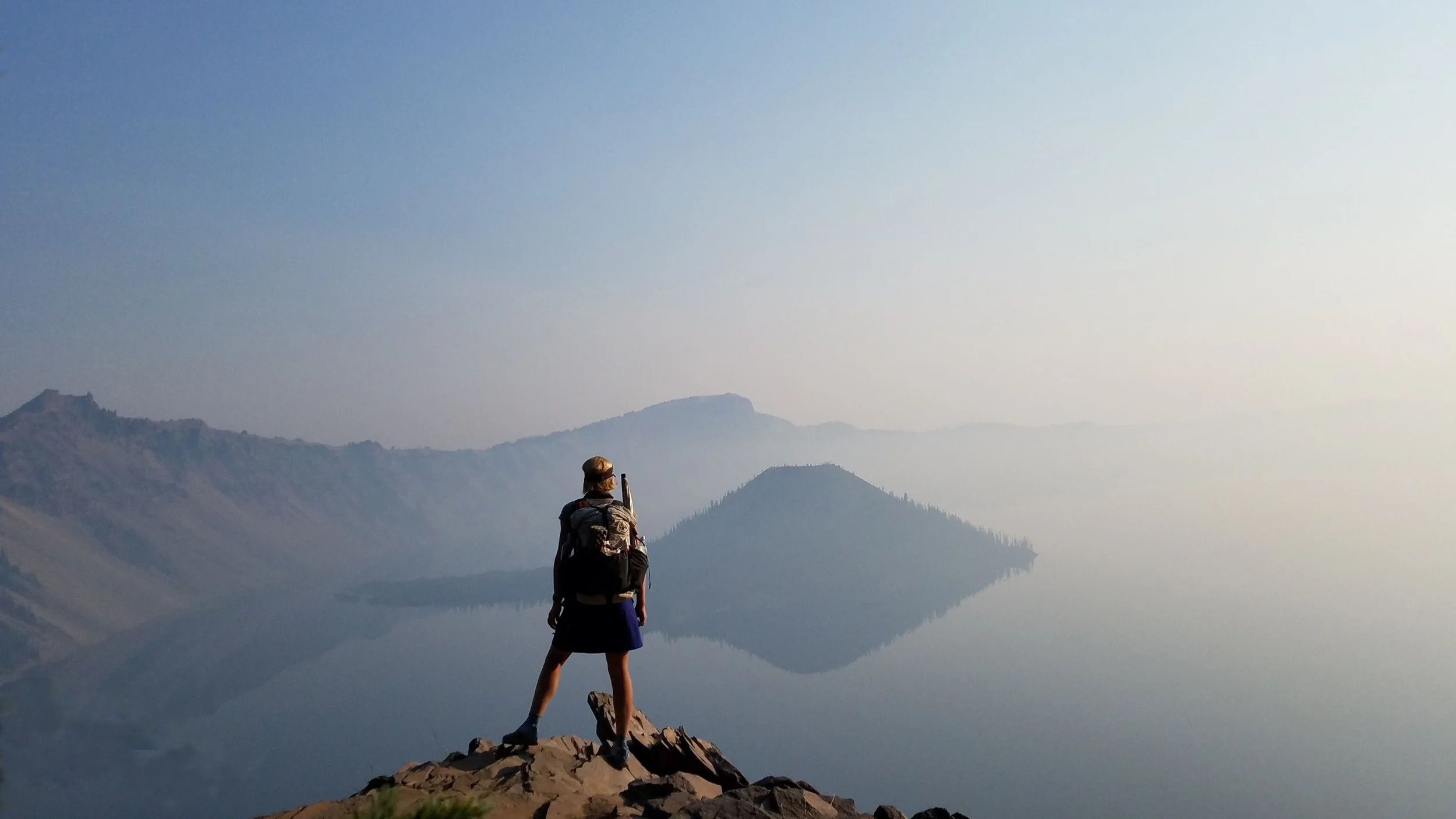 Backpacker standing on a rock overlooking Crater Lake