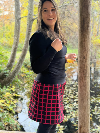 Woman standing outdoors in a forest with autumn foliage, holding a glass